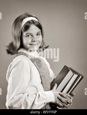 Negli anni sessanta la ragazza sorridente medio studente della scuola libri di testo Porta guardando la telecamera - s17066 HAR001 HARS ARCHETTO DI FIDUCIA B&W contatto visivo di grado scuole felicità il ponticello allegro TEXTBOOK ACCONCIATURA CONOSCENZA CAMICETTA PRETEEN sorrisi primaria gioiosa elegante GRADE SCHOOL LA CRESCITA I RAGAZZI DELLA SCUOLA MEDIA DI PRE-TEEN pre-teen ragazza in bianco e nero di etnia caucasica HAR001 in vecchio stile Foto Stock