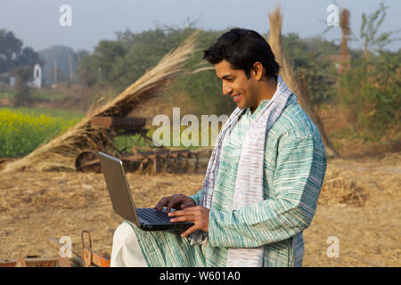 Farmer using a laptop in a field Stock Photo