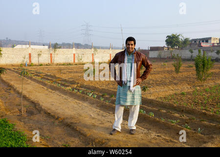 Agricoltore in piedi in un campo con bracci akimbo Foto Stock