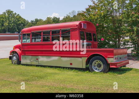 SPINDALE, NC, Stati Uniti d'America-27 luglio 19: un rosso scuola convertito convertito in un camper con un 'veranda sul retro' e grill, imposta in un prato molto su un giorno d'estate. Foto Stock