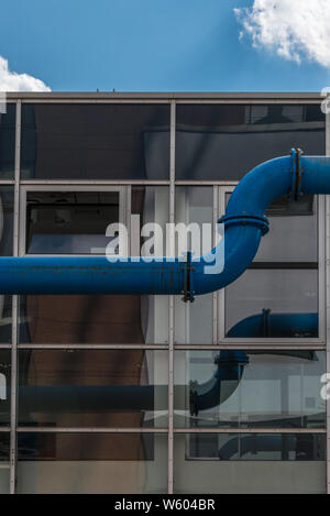 Ferro blu tubo di acqua nella parte anteriore di una facciata di vetro Foto Stock