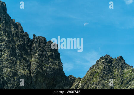 Mountain peak isolated on blue sky with moon Foto Stock