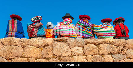 Un colorato gruppo di donne indigene Quechua che siedono su un antico muro Inca nelle rovine di Chinchero, Cusco, Perù. Foto Stock