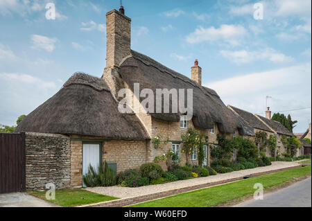 Una stretta viuzza con romantiche case in paglia e cottage in pietra nel grazioso Minster Lovell village, Cotswolds, Oxfordshire, Inghilterra Foto Stock