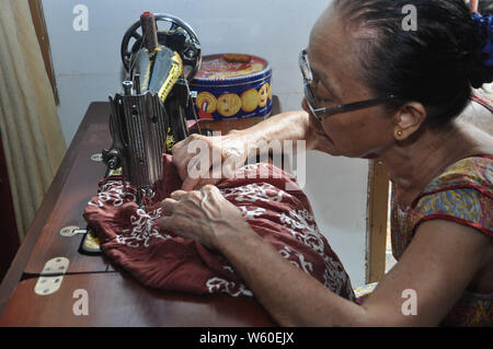 Dortje Nony, 73, cuce un panno in casa sua. Mrs.Nony si prende cura del suo marito Andarias Sarra, 80, una corsa vittima che sopravvivere da due attacchi di corsa Foto Stock
