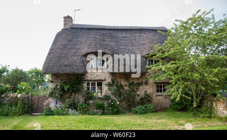 Una stretta viuzza con romantiche case in paglia e cottage in pietra nel grazioso Minster Lovell village, Cotswolds, Oxfordshire, Inghilterra Foto Stock