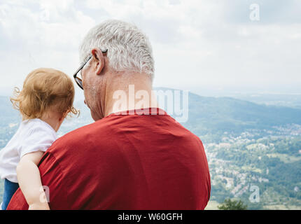 Baden-Baden, Germania - Luglio 7, 2019: vista posteriore del senior nonno maschio con i capelli bianchi azienda bambino Foto Stock