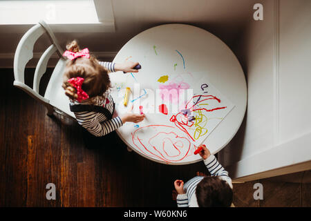 Ragazza giovane ragazzo e tecnica di pittura sul piccolo tavolo bianco interno Foto Stock