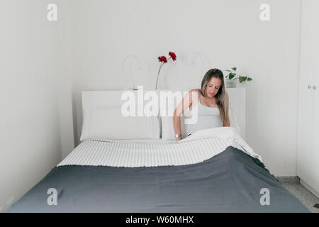 Incinta donna bionda che giace a letto malato Foto Stock