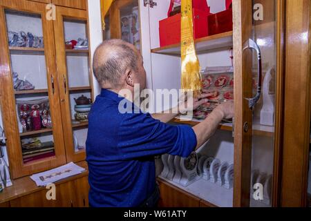 Il cinese anziano uomo Huang Junde Visualizza badge del ritratto del compianto Presidente Mao Zedong ha raccolto in questi ultimi cinquant'anni nella sua casa di Chong Foto Stock