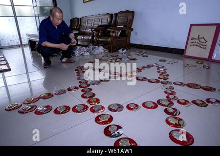 Il cinese anziano uomo Huang Junde Visualizza badge del ritratto del compianto Presidente Mao Zedong ha raccolto in questi ultimi cinquant'anni nella sua casa di Chong Foto Stock