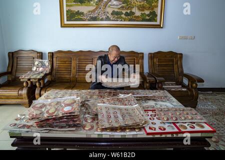 Il cinese anziano uomo Huang Junde Visualizza badge del ritratto del compianto Presidente Mao Zedong ha raccolto in questi ultimi cinquant'anni nella sua casa di Chong Foto Stock