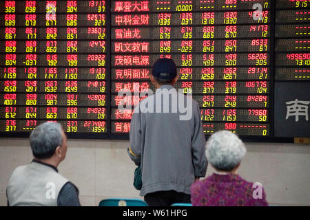 --FILE--investitori cinesi guardare un display elettronico che mostra i prezzi delle azioni (rosso per il prezzo in aumento e verde per la caduta dei prezzi) in corrispondenza di un magazzino brokera Foto Stock