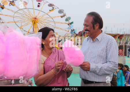 Vecchia coppia mangiare caramelle di cotone in una fiera, Surajkund, Faridabad, Haryana, India Foto Stock