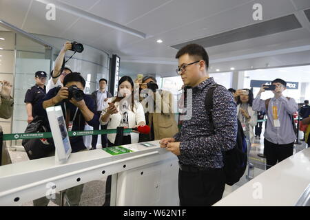 Un passeggero che scandisce la sua carta d'imbarco su un self-service di salire a bordo di una macchina equipaggiata con il riconoscimento facciale della capacità a T1, terminale di Shanghai ho Foto Stock