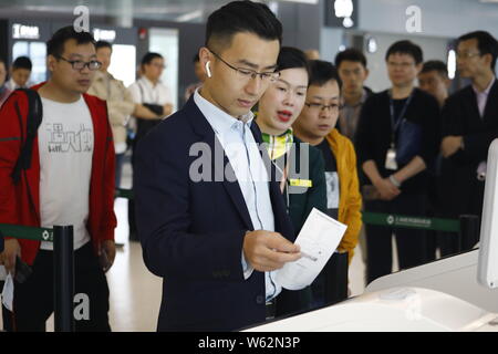 Un passeggero che scandisce la sua carta d'imbarco su un self-service di salire a bordo di una macchina equipaggiata con il riconoscimento facciale della capacità a T1, terminale di Shanghai ho Foto Stock