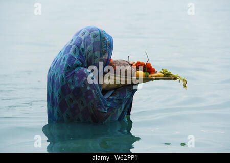 Donna che prega in un fiume durante chhath puja festival Foto Stock