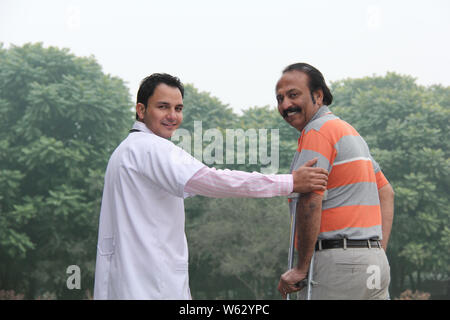 Fisioterapista che aiuta il paziente a camminare Foto Stock