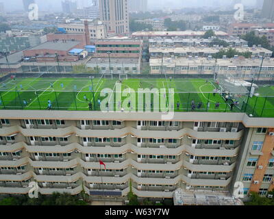 In questa vista aerea, i bambini di giocare a calcio in uno stadio di calcio costruito sul tetto della Scuola Primaria collegata al normale di Shandong University in Foto Stock