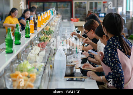 Gli studenti mangiare nastro trasportatore hotpot, letteralmente 'Rotazione hot pot,' in una mensa di Xi'an università di finanza ed economia in Xi'an City, Northwest Ch Foto Stock