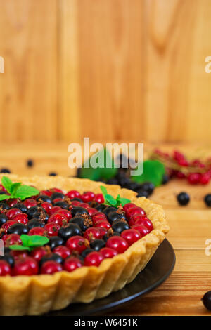 Deliziosa torta con crema pasticcera e ribes su sfondo di legno Foto Stock