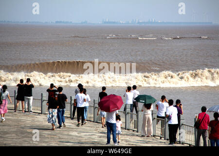 I visitatori e i residenti locali guardare onde da un foro di marea del Fiume Qiantang sgorga sopra la banca di fiume in Haining City, est della Cina di Zhejiang provin Foto Stock