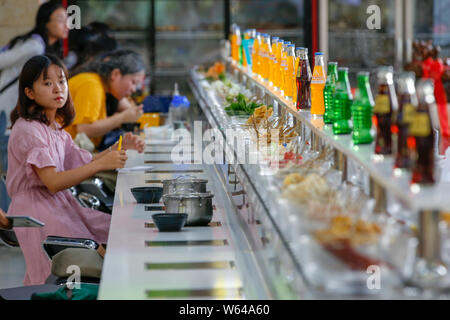 Gli studenti mangiare nastro trasportatore hotpot, letteralmente 'Rotazione hot pot,' in una mensa di Xi'an università di finanza ed economia in Xi'an City, Northwest Ch Foto Stock