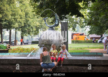 La madre e le figlie godendo di rimanere al fontana nella parte interna della città di Mainz, Germania Foto Stock