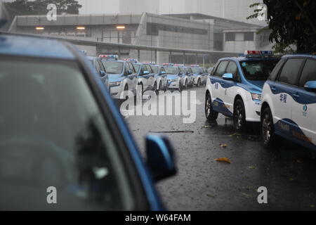 I taxi in coda fino a essere ricaricata in Pesanti rovesci di pioggia e forte vento causato dal tifone Mangkhut, la ventiduesima typhoon dell'anno, a fronte di un charing sta Foto Stock