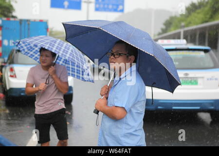 I taxi in coda fino a essere ricaricata in Pesanti rovesci di pioggia e forte vento causato dal tifone Mangkhut, la ventiduesima typhoon dell'anno, a fronte di un charing sta Foto Stock