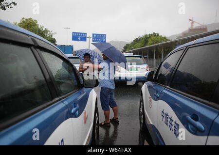 I taxi in coda fino a essere ricaricata in Pesanti rovesci di pioggia e forte vento causato dal tifone Mangkhut, la ventiduesima typhoon dell'anno, a fronte di un charing sta Foto Stock