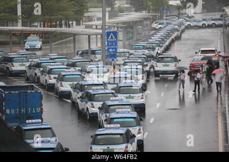 I taxi in coda fino a essere ricaricata in Pesanti rovesci di pioggia e forte vento causato dal tifone Mangkhut, la ventiduesima typhoon dell'anno, a fronte di un charing sta Foto Stock