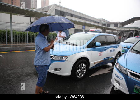 I taxi in coda fino a essere ricaricata in Pesanti rovesci di pioggia e forte vento causato dal tifone Mangkhut, la ventiduesima typhoon dell'anno, a fronte di un charing sta Foto Stock