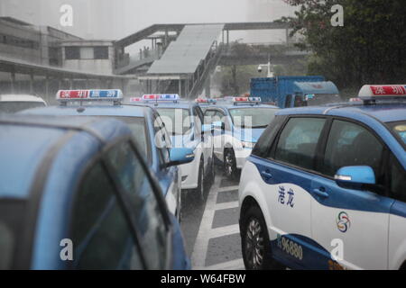 I taxi in coda fino a essere ricaricata in Pesanti rovesci di pioggia e forte vento causato dal tifone Mangkhut, la ventiduesima typhoon dell'anno, a fronte di un charing sta Foto Stock