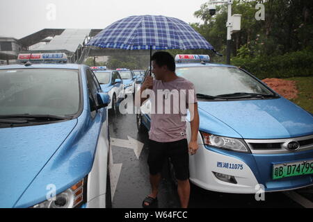 I taxi in coda fino a essere ricaricata in Pesanti rovesci di pioggia e forte vento causato dal tifone Mangkhut, la ventiduesima typhoon dell'anno, a fronte di un charing sta Foto Stock