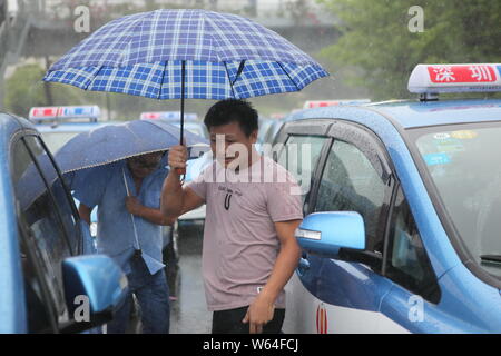 I taxi in coda fino a essere ricaricata in Pesanti rovesci di pioggia e forte vento causato dal tifone Mangkhut, la ventiduesima typhoon dell'anno, a fronte di un charing sta Foto Stock