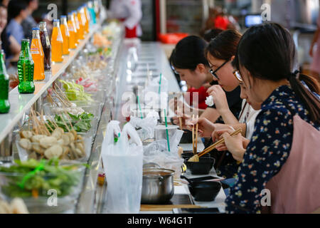 Gli studenti mangiare nastro trasportatore hotpot, letteralmente 'Rotazione hot pot,' in una mensa di Xi'an università di finanza ed economia in Xi'an City, Northwest Ch Foto Stock