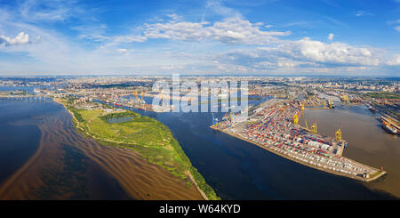 Antenna di vista panoramica sul porto di mare con container a San Pietroburgo, Russia contro la città lontana e cielo molto nuvoloso Foto Stock