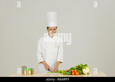 Lo chef femmina nella preparazione degli alimenti e sorridente Foto Stock