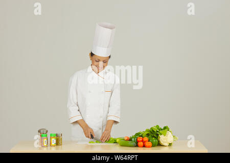 Lo chef femmina nella preparazione degli alimenti e sorridente Foto Stock