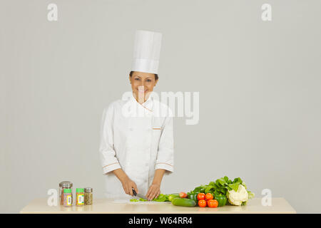 Lo chef femmina nella preparazione degli alimenti e sorridente Foto Stock