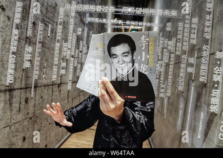 Un membro del personale di Chengdu Yan Ji Bookstore si pone per una prospettiva forzata fotografia con un libro con il ritratto di Hong Kong e attore americano Foto Stock