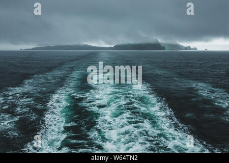 Vestmannaeyjar isole dell arcipelago in Islanda. Vista dal traghetto. Drammatico paesaggio nordico con nebbia e nuvole basse. Foto Stock