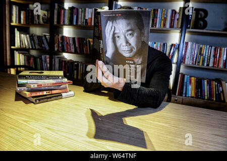 Un membro del personale di Chengdu Yan Ji Bookstore si pone per una prospettiva forzata fotografia con un libro con il ritratto dello scrittore giapponese Haruki Murak Foto Stock