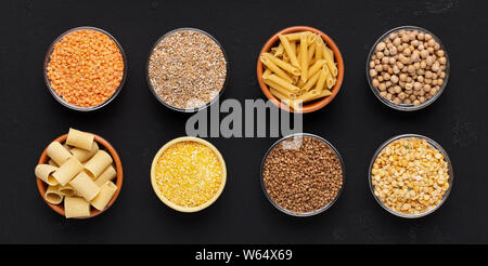 Set di grani e tagliatelle ricche di carboidrati in piastre su nero Foto Stock
