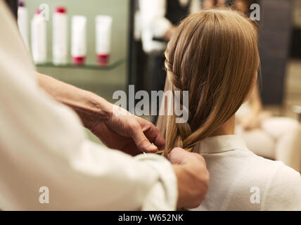 Parrucchiere intreccio di giovane donna capelli in un salone di bellezza, Primo Piano Foto Stock