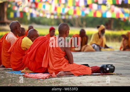 I monaci buddisti in meditazione sotto la bandiera di preghiera Foto Stock