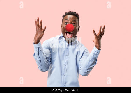 Ritratto di giovane uomo felice celebrando naso rosso al giorno. African maschio modello sguardi stupiti in rosa di sfondo per studio. La vittoria, delizia concetto. Viso umano emozioni, concetto di espressione. Colori alla moda. Foto Stock