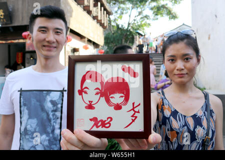 Un giovane visualizza una carta-taglio effettuato dal folk cinese artista Xie Jianqing per la prossima festa Qixi o 'Double sette Festival", noto anche come il ch Foto Stock