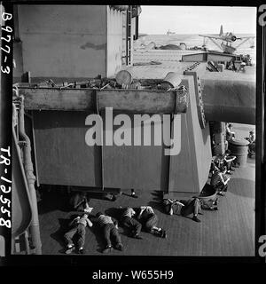 Uomini arruolati rilassante durante off-dovere ore a bordo della USS New Jersey (BB-62) OS2U su di una catapulta in background. Foto Stock